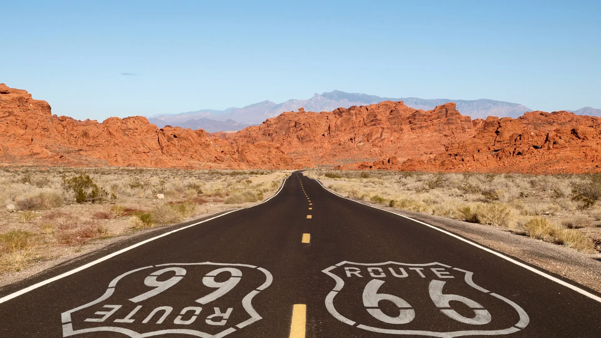 shutterstock_121945762 Route 66 pavement sign with Mojave desert red rock mountains..jpg