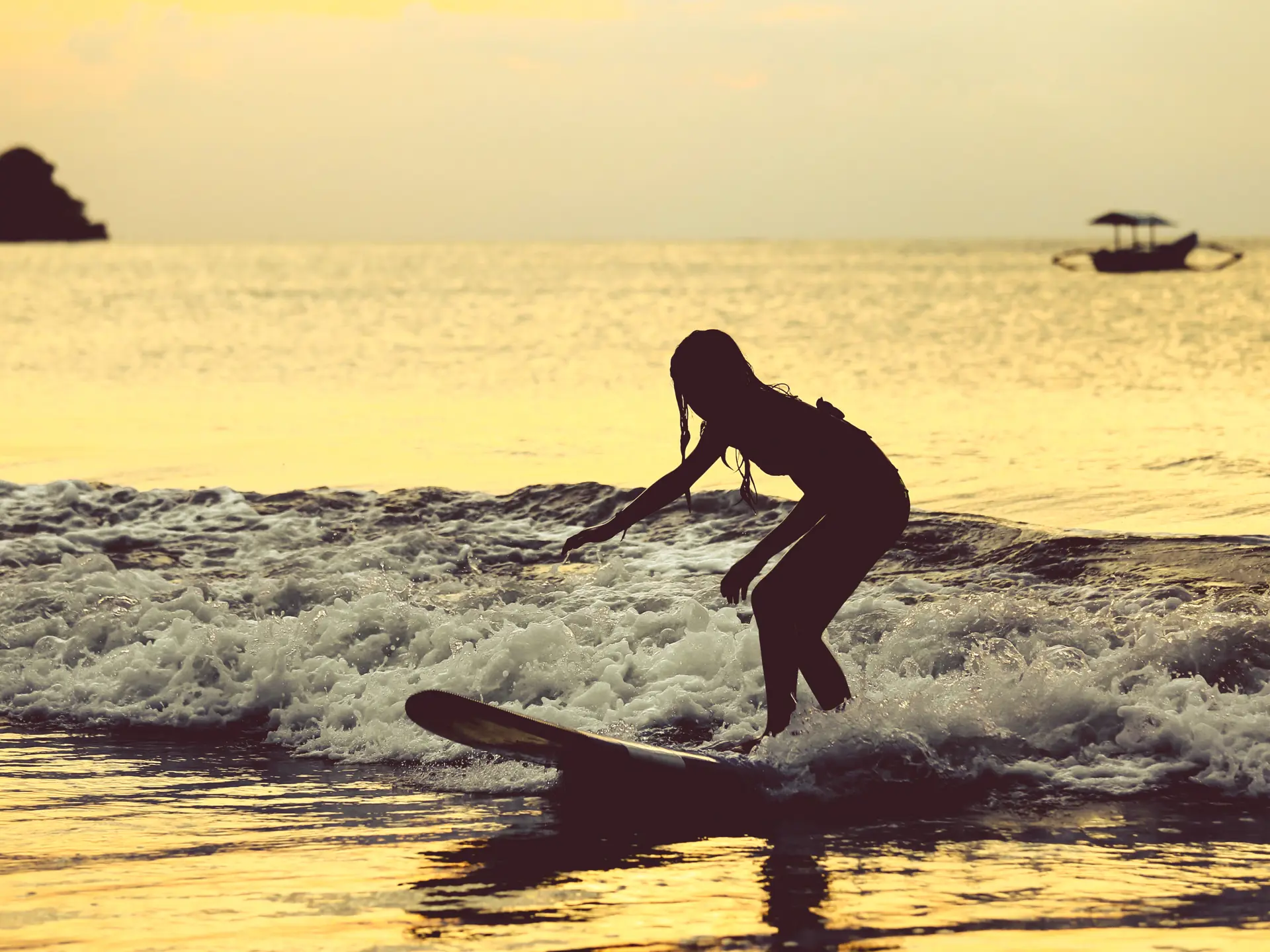shutterstock_492020038 Silhouette of surfer girl surfing on her board on the tropical Jimbaran beach..jpg