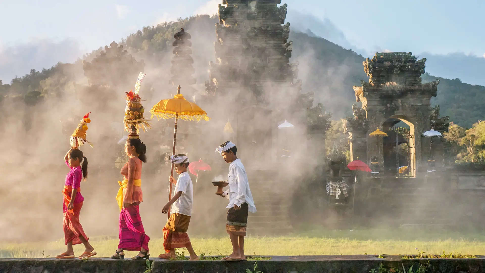 shutterstock_1053593438 Ubud, Bali - July 30, 2016. Illustrative Editorial. Showing traditional Balinese male and female ceremonial clothing and religious offerings, as a mother and children walk to a Hindu.jpg