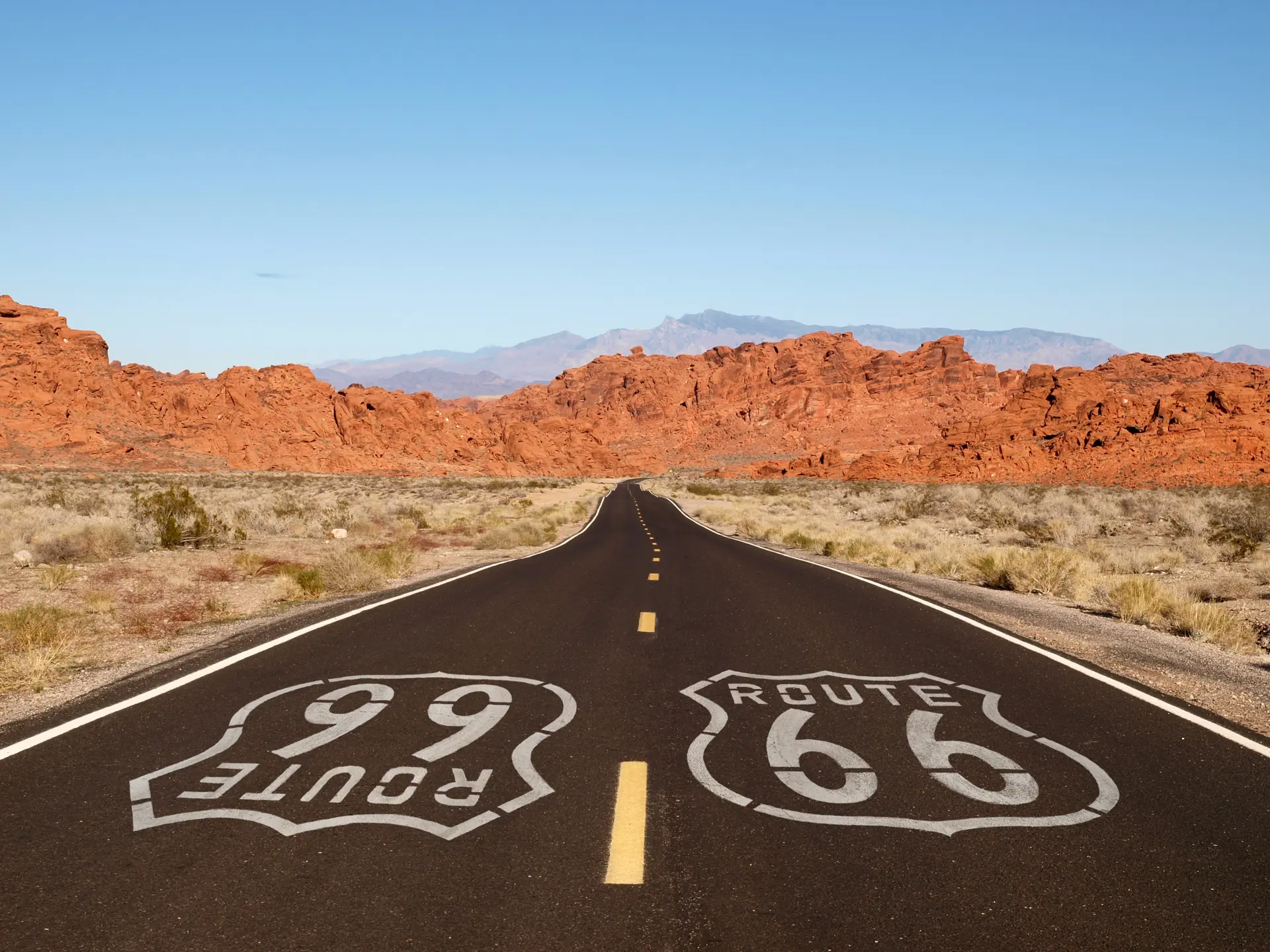 shutterstock_121945762 Route 66 pavement sign with Mojave desert red rock mountains..jpg