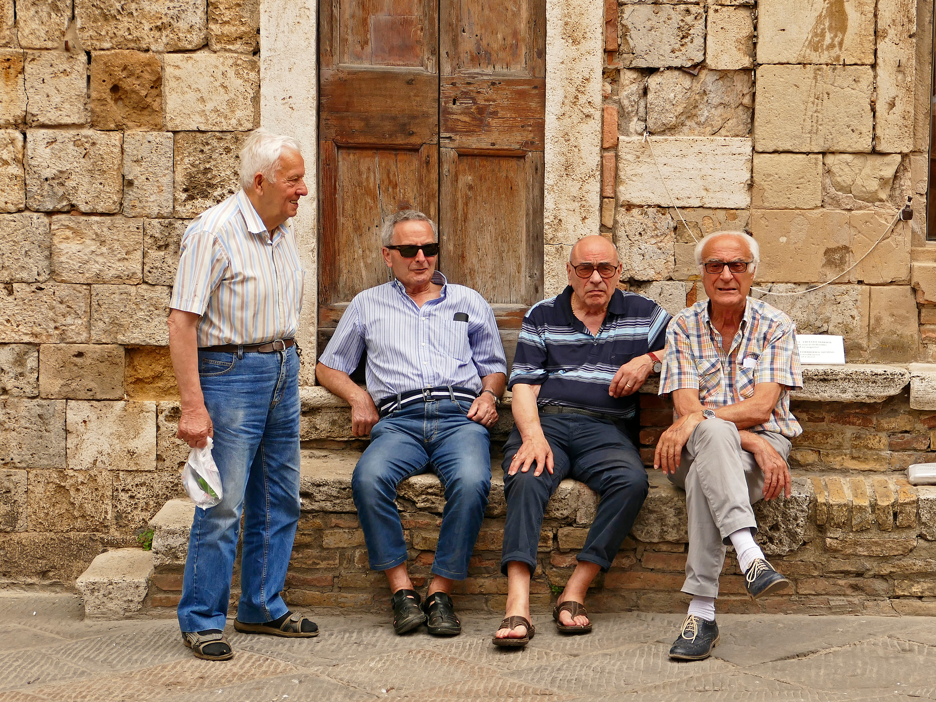 Gamle venner slår av en prat på et torg i San Gimignano