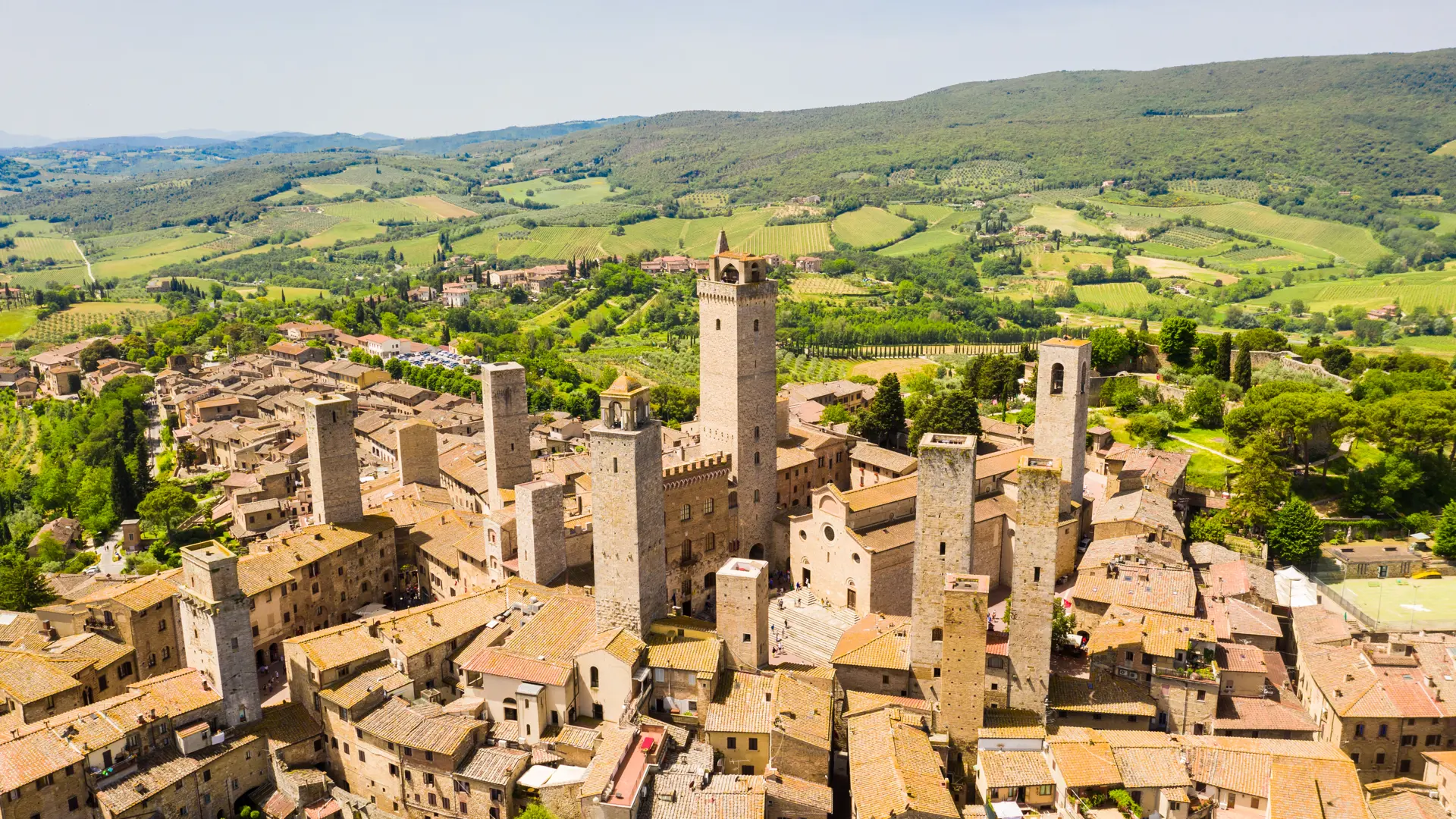 Den gamle middelalderbyen San Gimignano omgitt av det bølgende grønne landskapet i Toscana