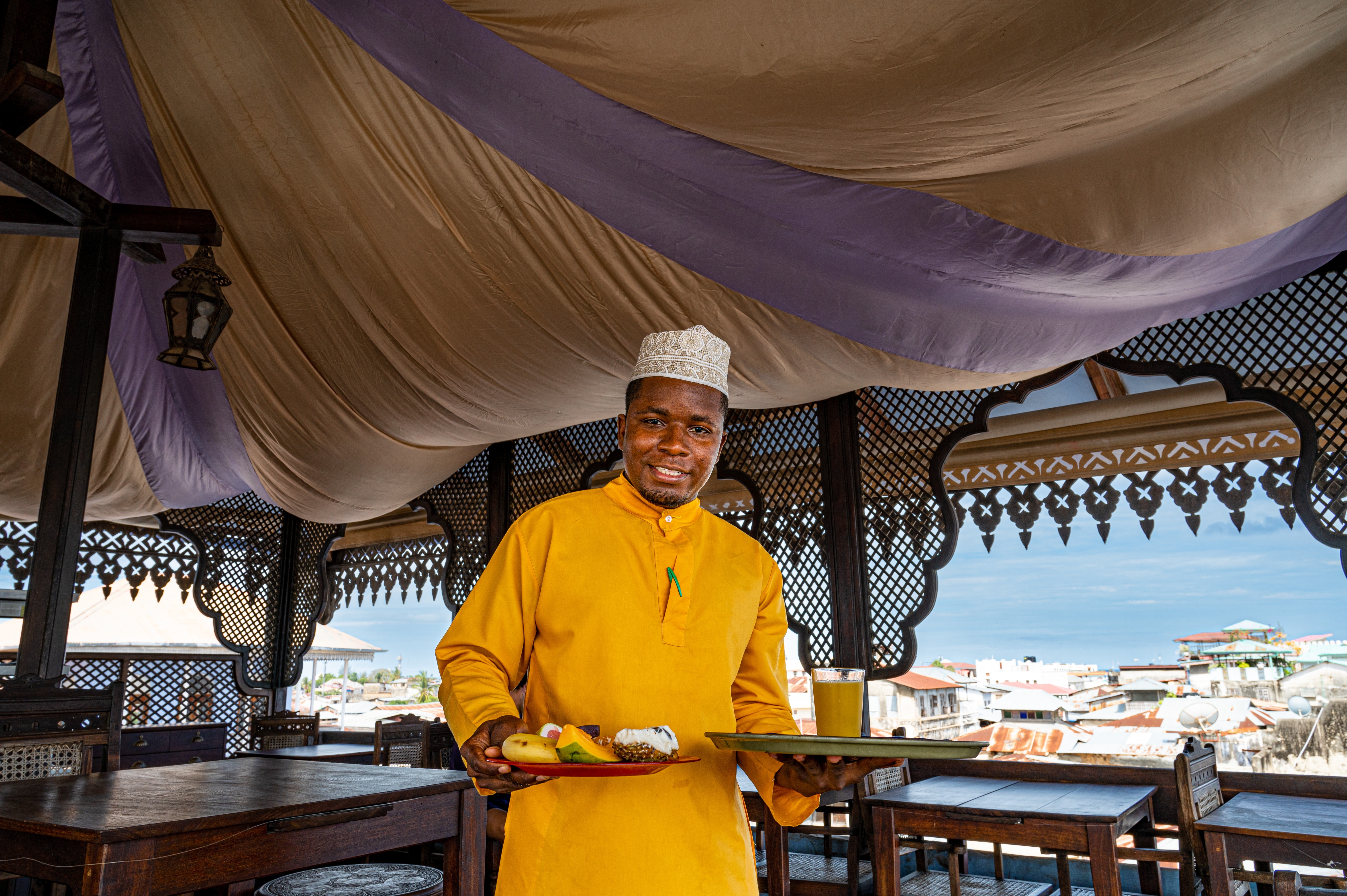Shutterstock 2223567971 Stone Town, Zanzibar Tanzania March28,2021 Waiter Serving Breakfast On Rooftop Building In Stone Town Zanzibar