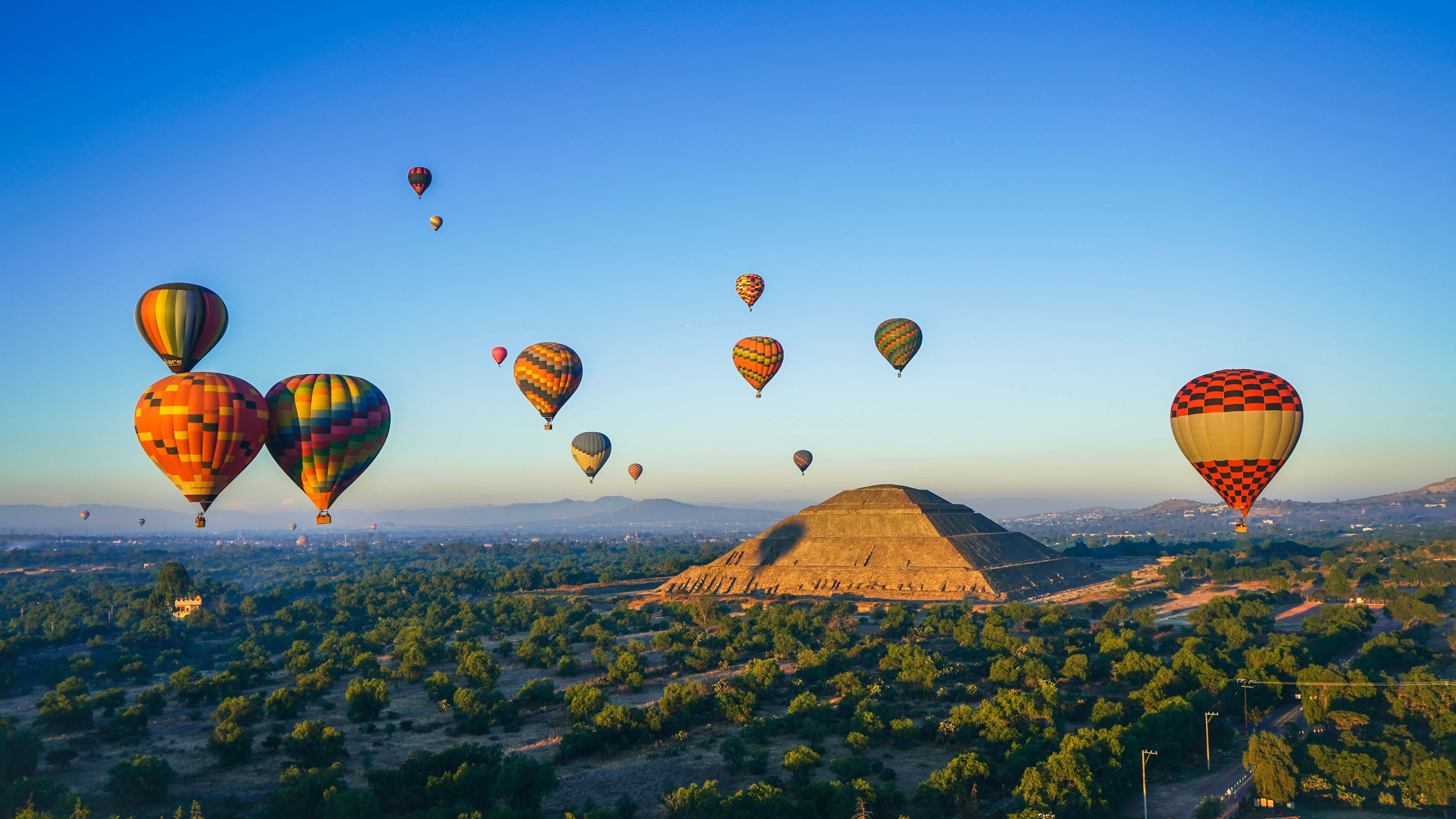 Dette billede fanger en populær turistoplevelse med varmluftballoner over Teotihuacan-pyramiderne i Mexico ved solopgang